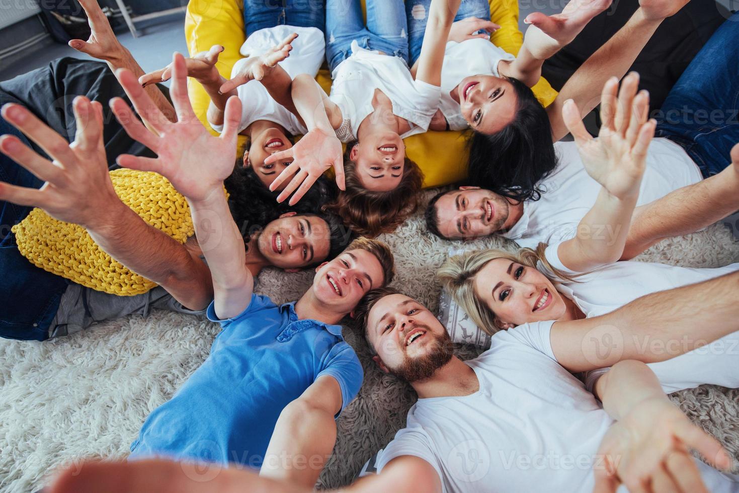 grupo de jóvenes hermosos haciendo selfie tirados en el suelo, mejores amigos niñas y niños juntos divirtiéndose, planteando un concepto de estilo de vida emocional foto