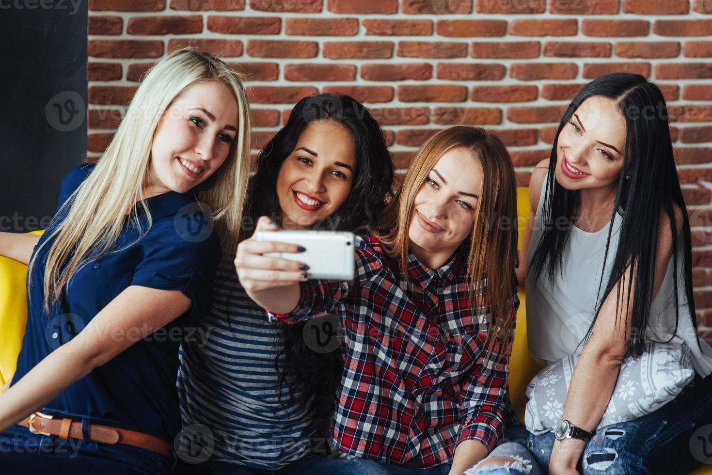 cuatro hermosas mujeres jóvenes haciendo selfie en un café, mejores amigas juntas divirtiéndose, planteando el concepto de personas de estilo de vida emocional foto