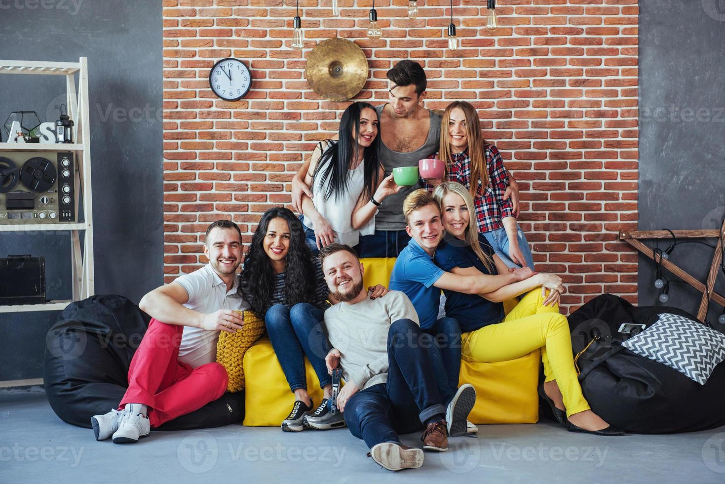 Group portrait of multi-ethnic boys and girls with colorful fashionable clothes holding friend posing on a brick wall, Urban style people having fun, Concepts about youth togetherness lifestyle photo