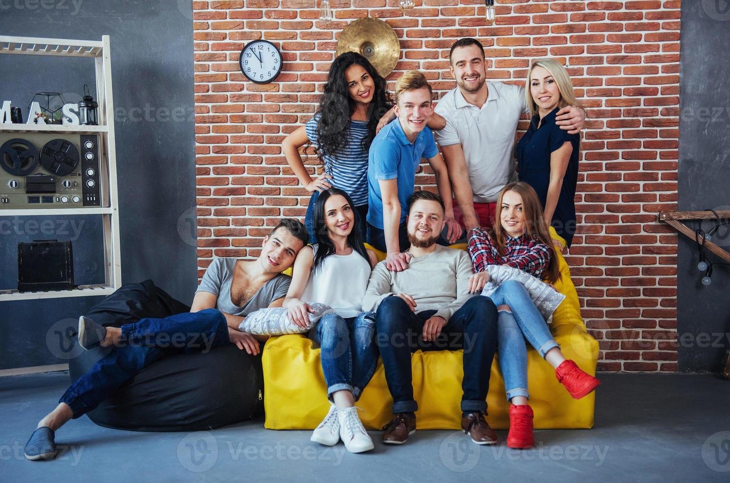 Group portrait of multi-ethnic boys and girls with colorful fashionable clothes holding friend posing on a brick wall, Urban style people having fun, Concepts about youth togetherness lifestyle photo