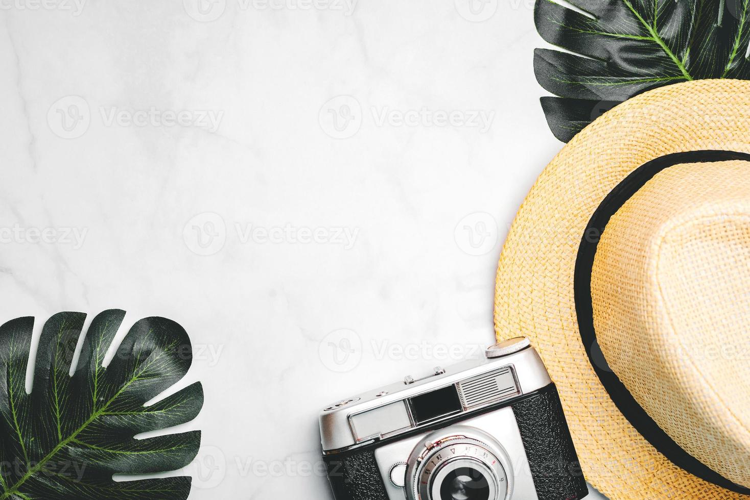 Straw hat with green tropical leaves and vintage photo camera with space for text.Vacation travel Concept