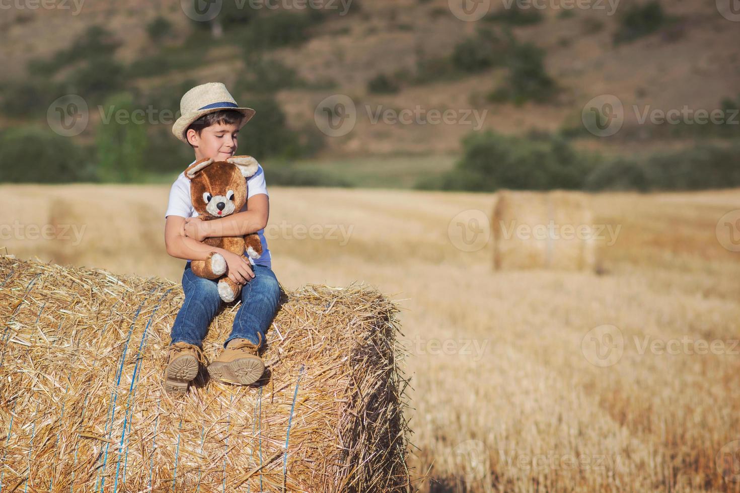 Boy hugging teddy bear in the wheat field photo