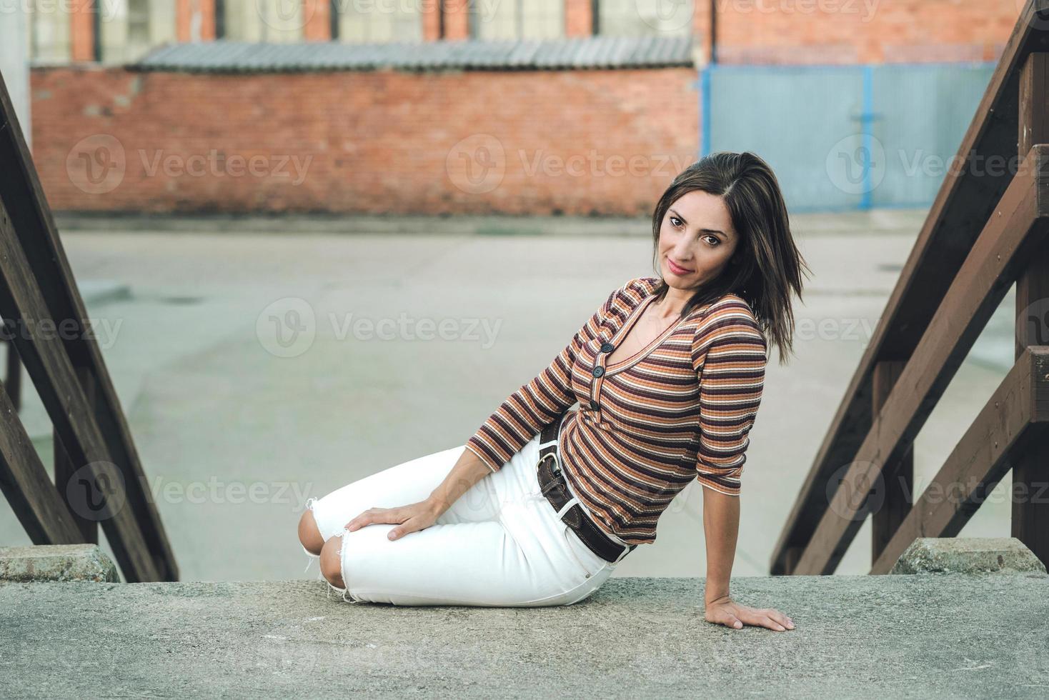 mujer joven sonriente sentada en la calle foto