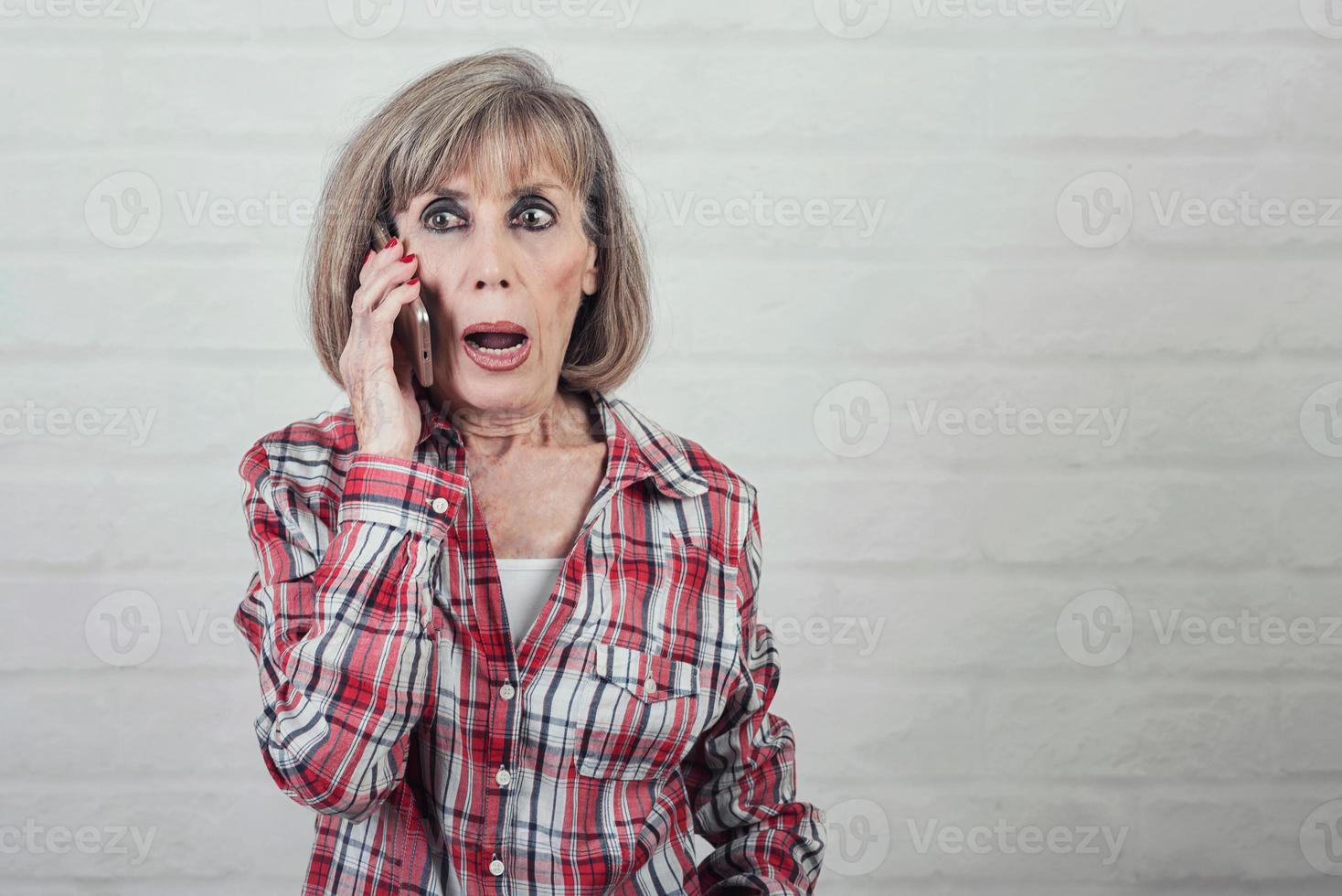 Surprised senior woman talking on a smartphone photo