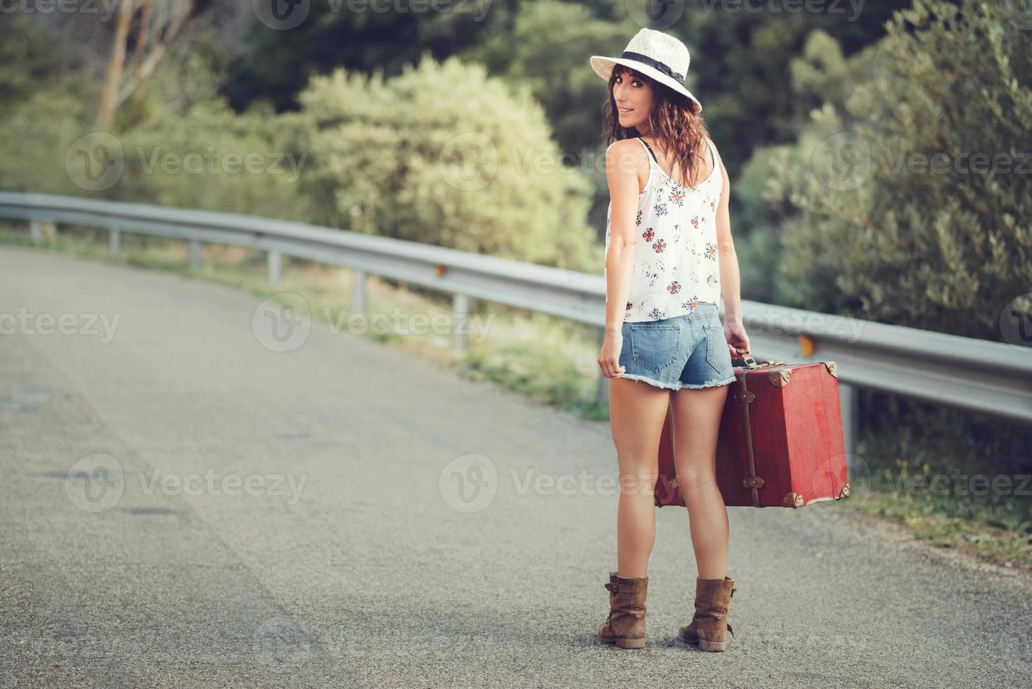 chica joven con una maleta en el camino foto