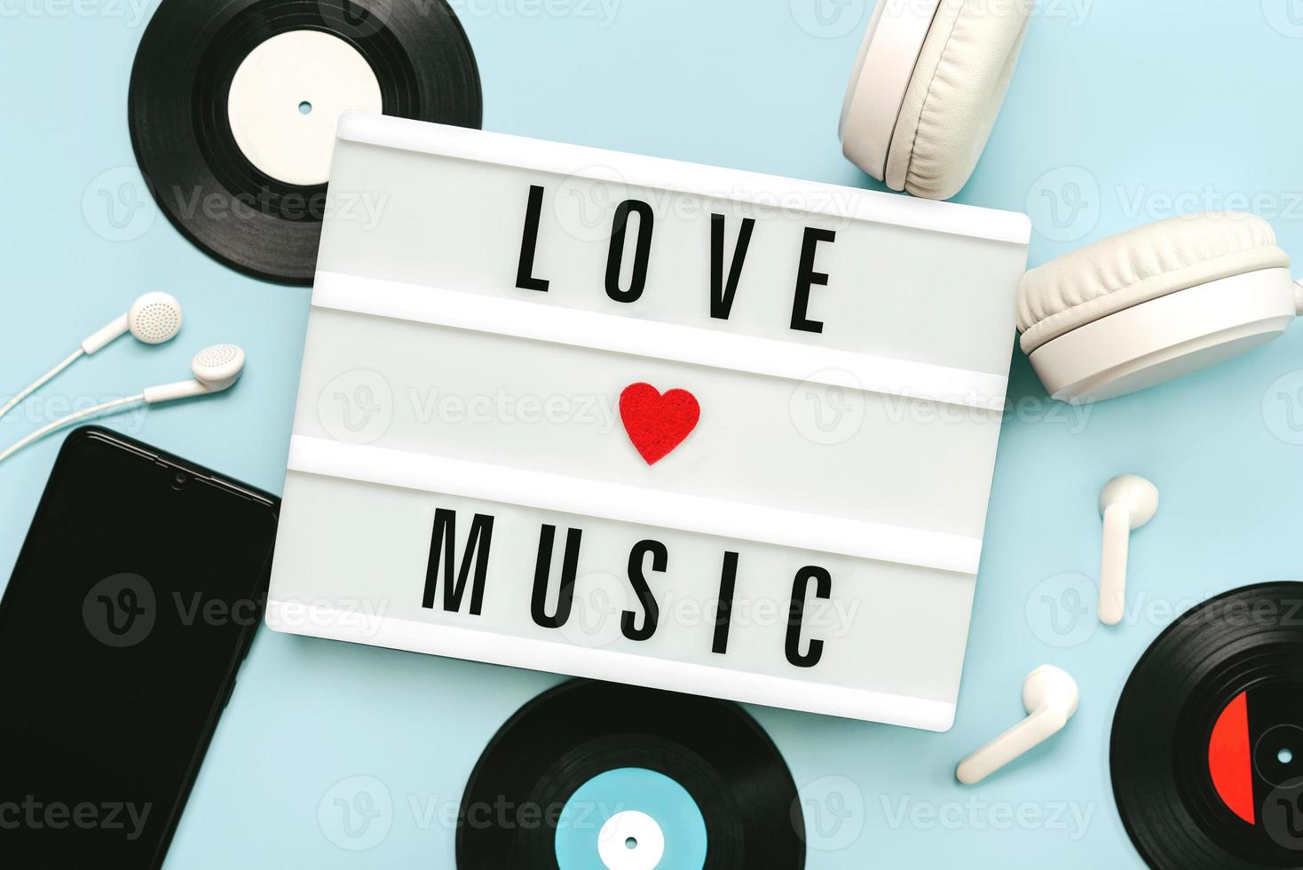 Lightbox with the text love music next to headphones,smartphone and vinyl discs photo