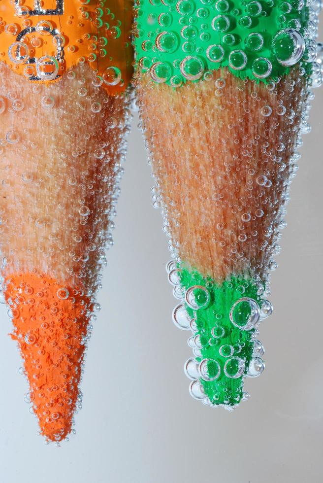 two crayons with tips in the water and lots of bubbles photo