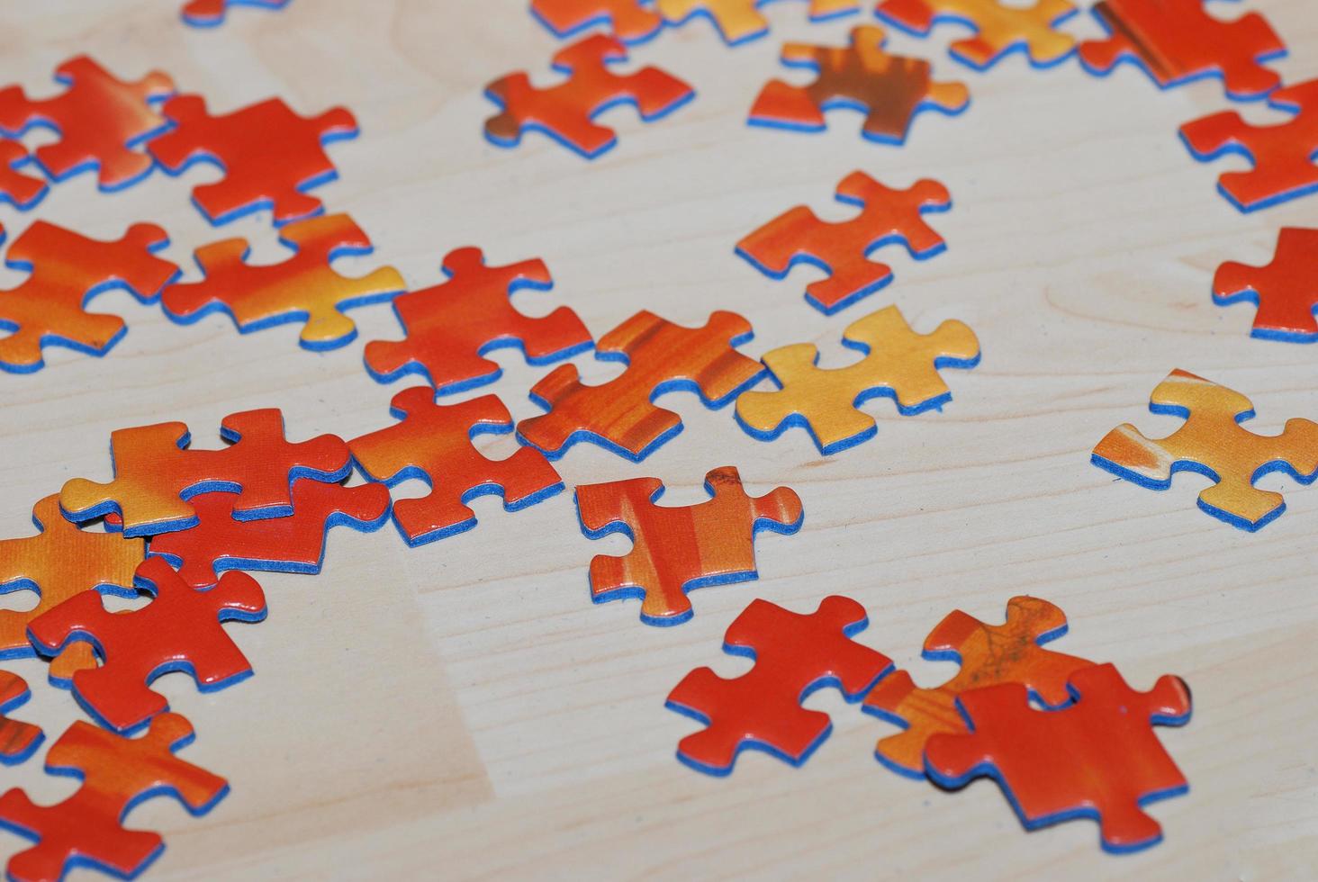 many orange puzzle pieces lie on wooden background ready to build and play photo