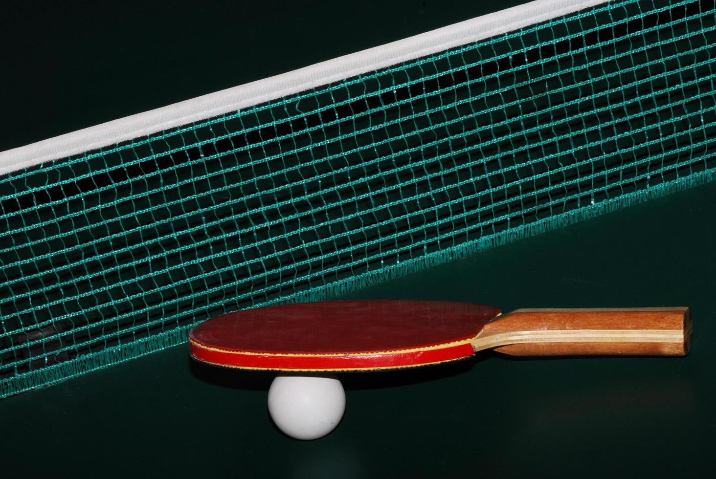 Pelota de raqueta de tenis de mesa y red en la mesa de tenis de mesa cerca foto