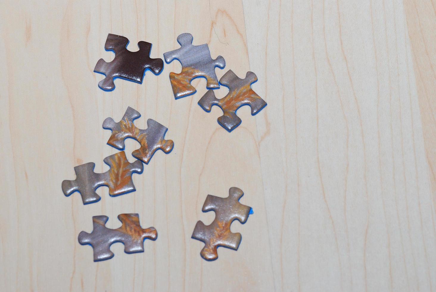 many puzzle pieces lie on wooden background ready to build and play photo