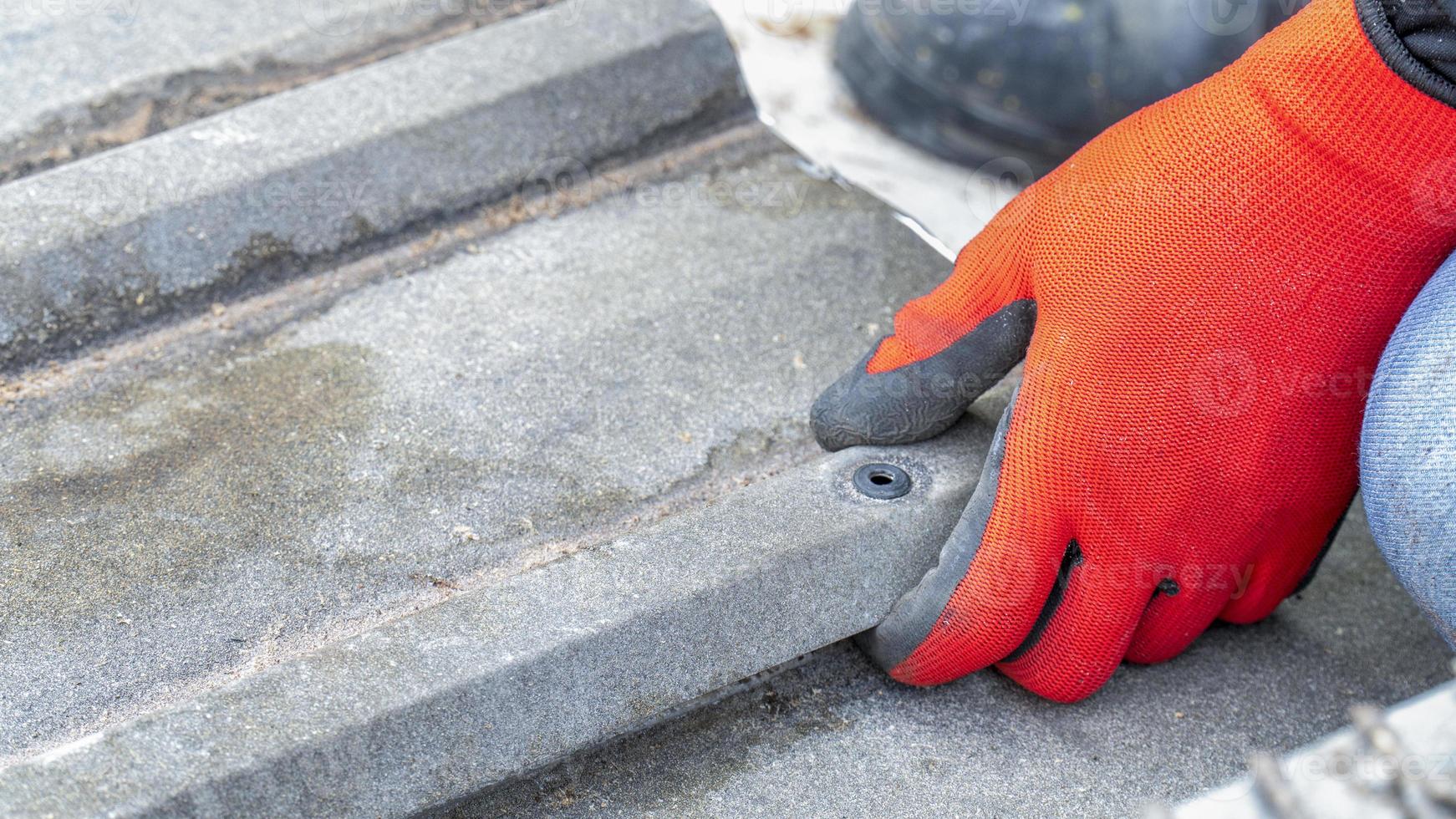 Workers wearing gloves use their hands to repair steel roofs. photo