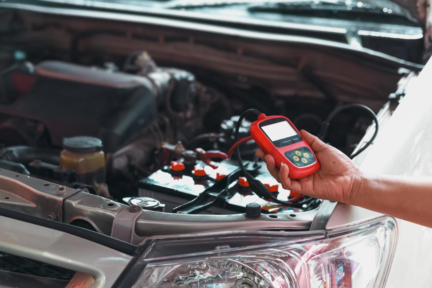 Mechanic using car battery performance meter photo