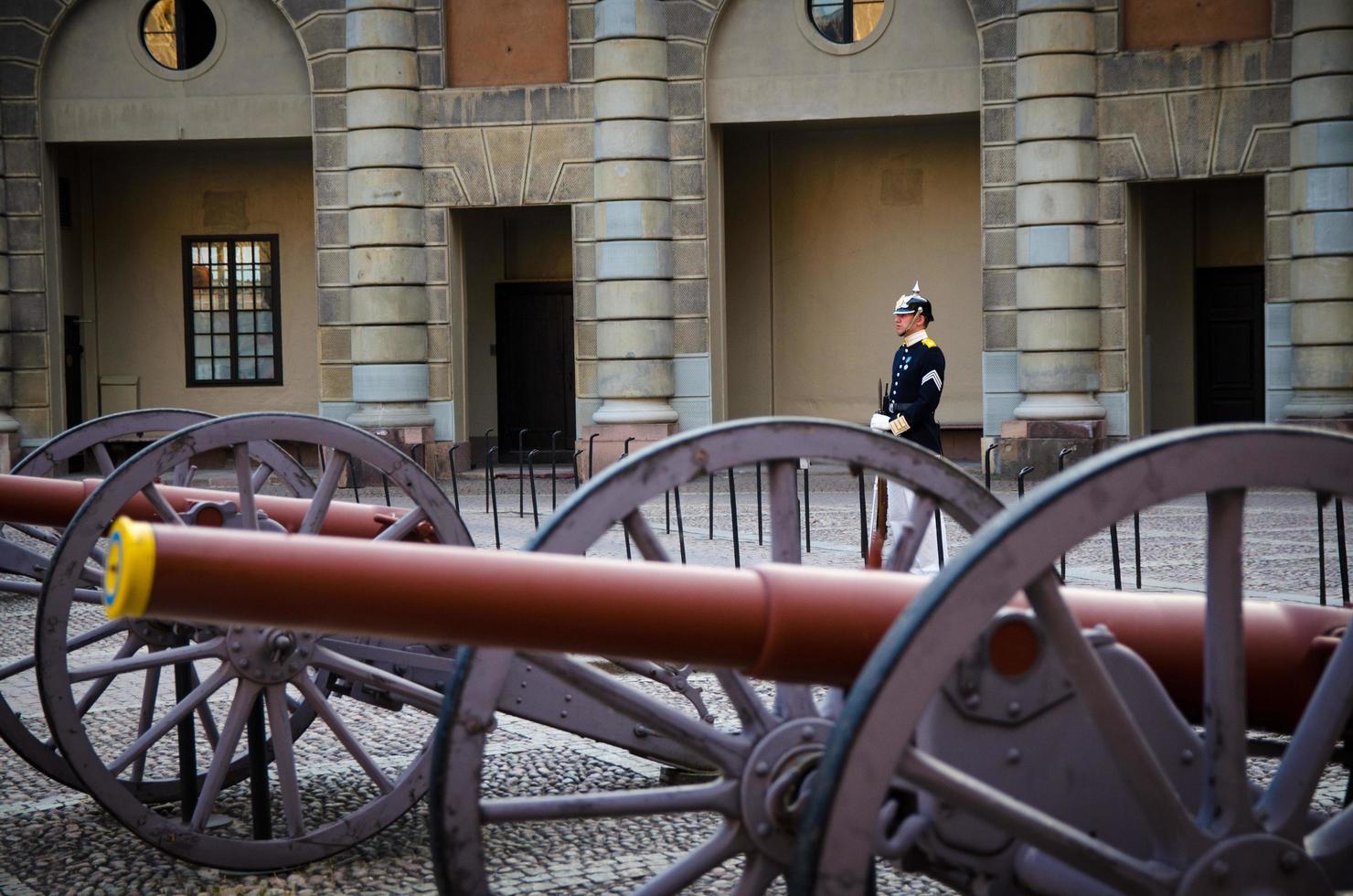 Guard soldier at post near row old cannons in courtyard square of Swedish Royal Palace official residence of King of Sweden photo