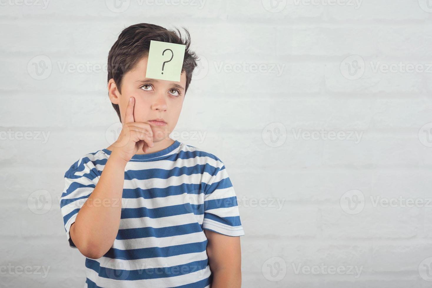 Child thinking with question mark in memo post on his forehead photo