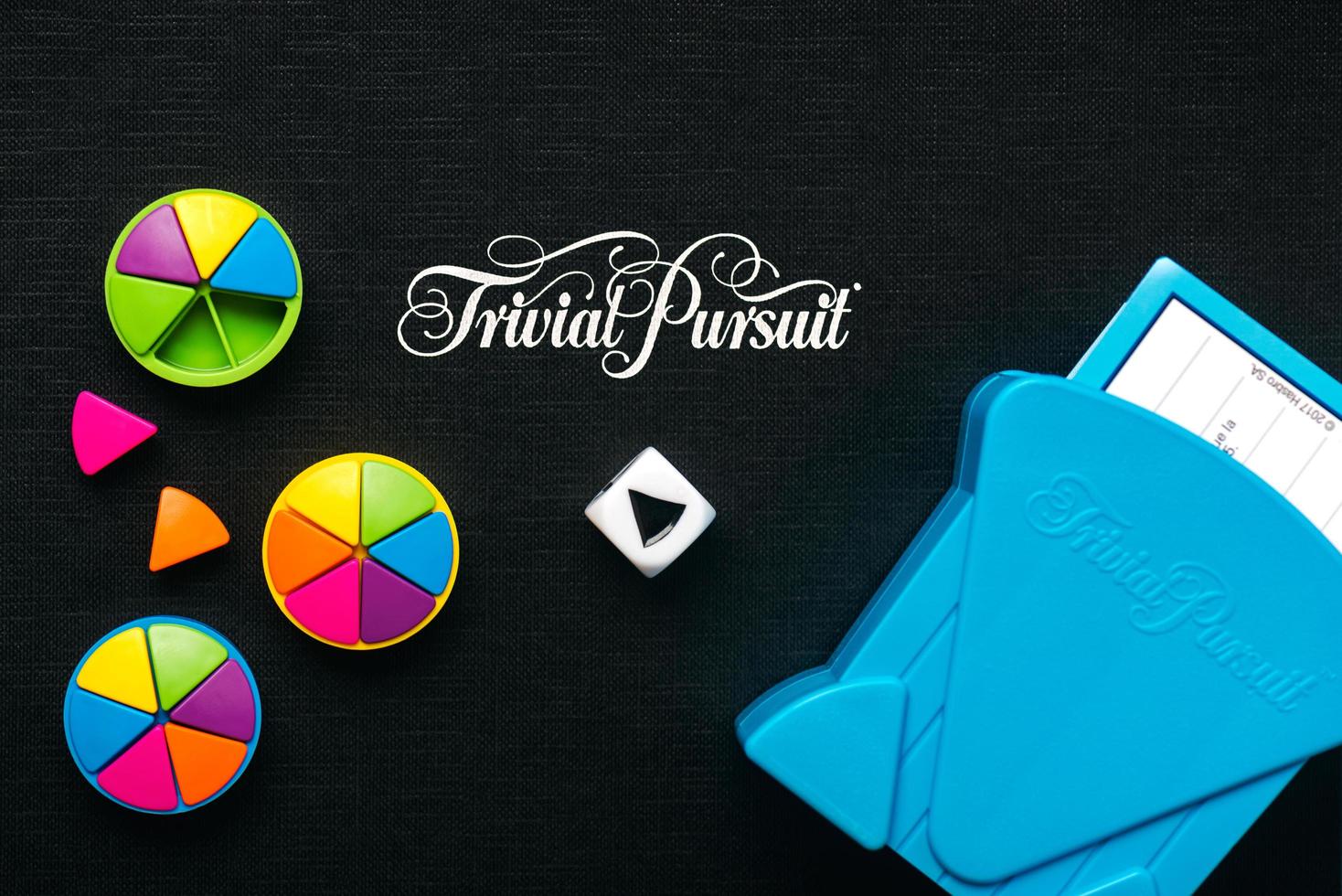 Black board game of Trivial Pursuit game with white die,colored plastic pieces and blue card holder photo