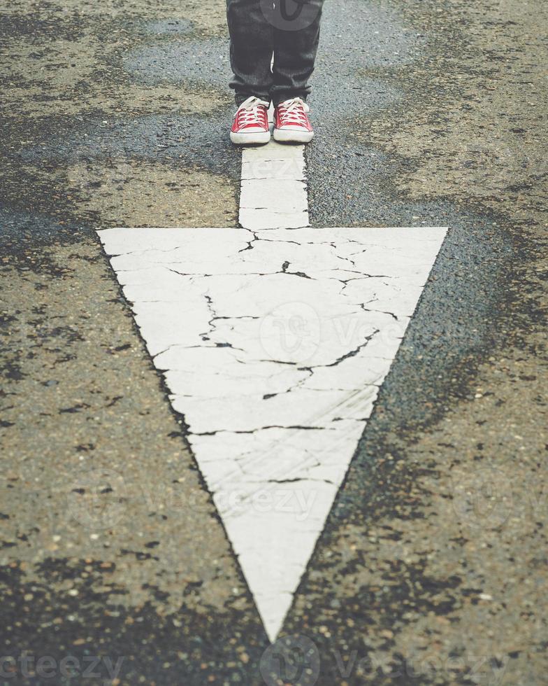 sneakers near the arrow marking of the road photo