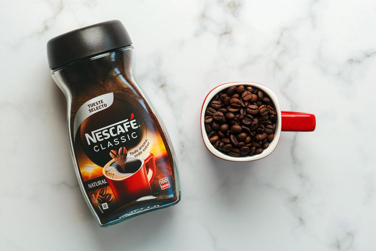 Jar of Nescafe Classic and red cup of Nescafe with coffee beans photo