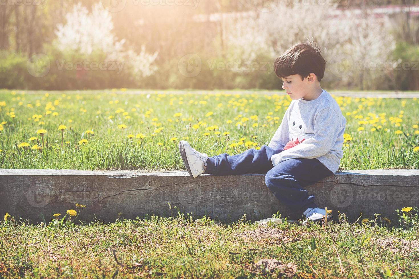 thoughtful child sitting on field photo