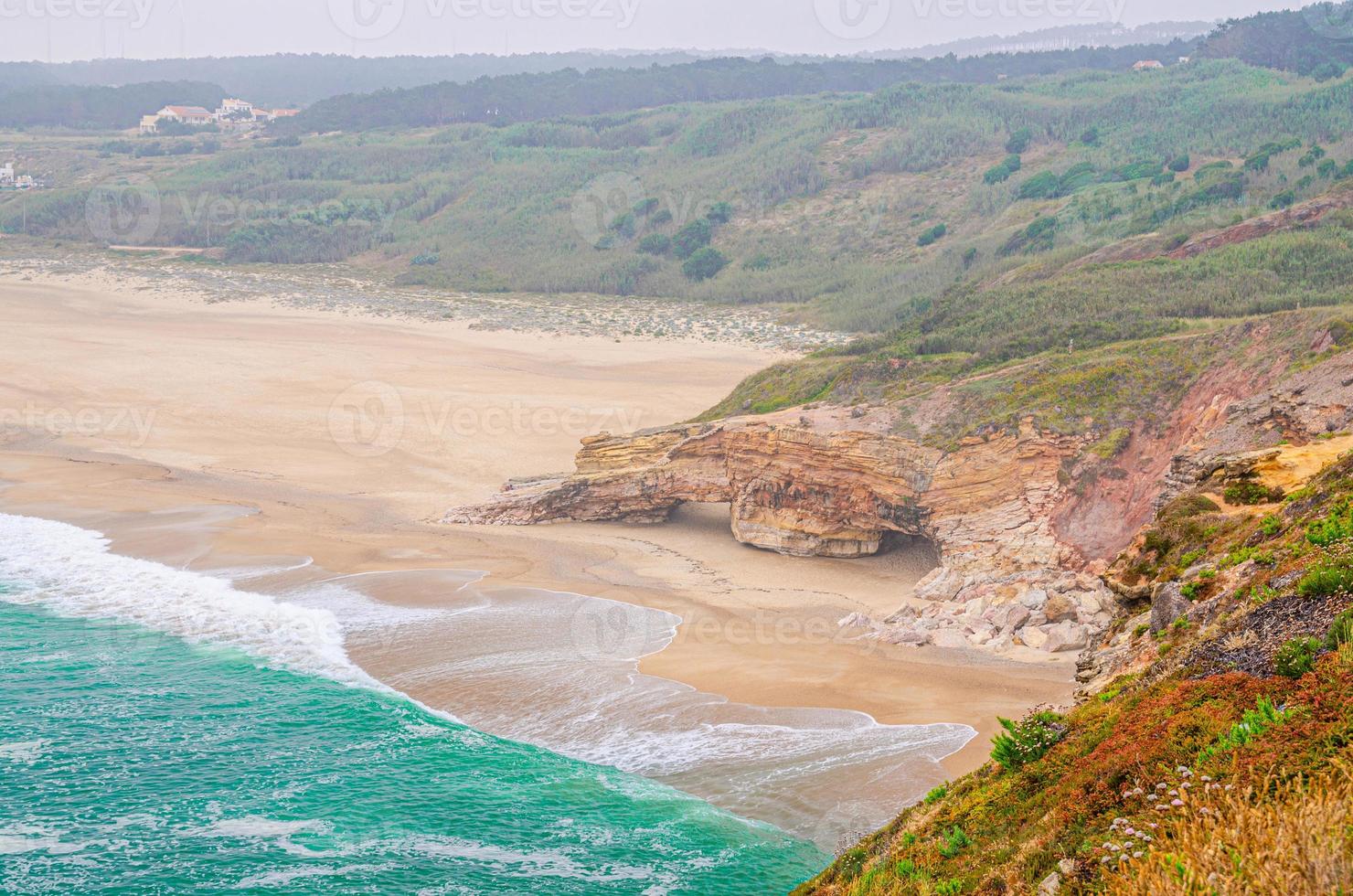 Top aerial view of sandy beach with rocks and cliffs and waves of azure turquoise water of Atlantic Ocean near Nazare town photo