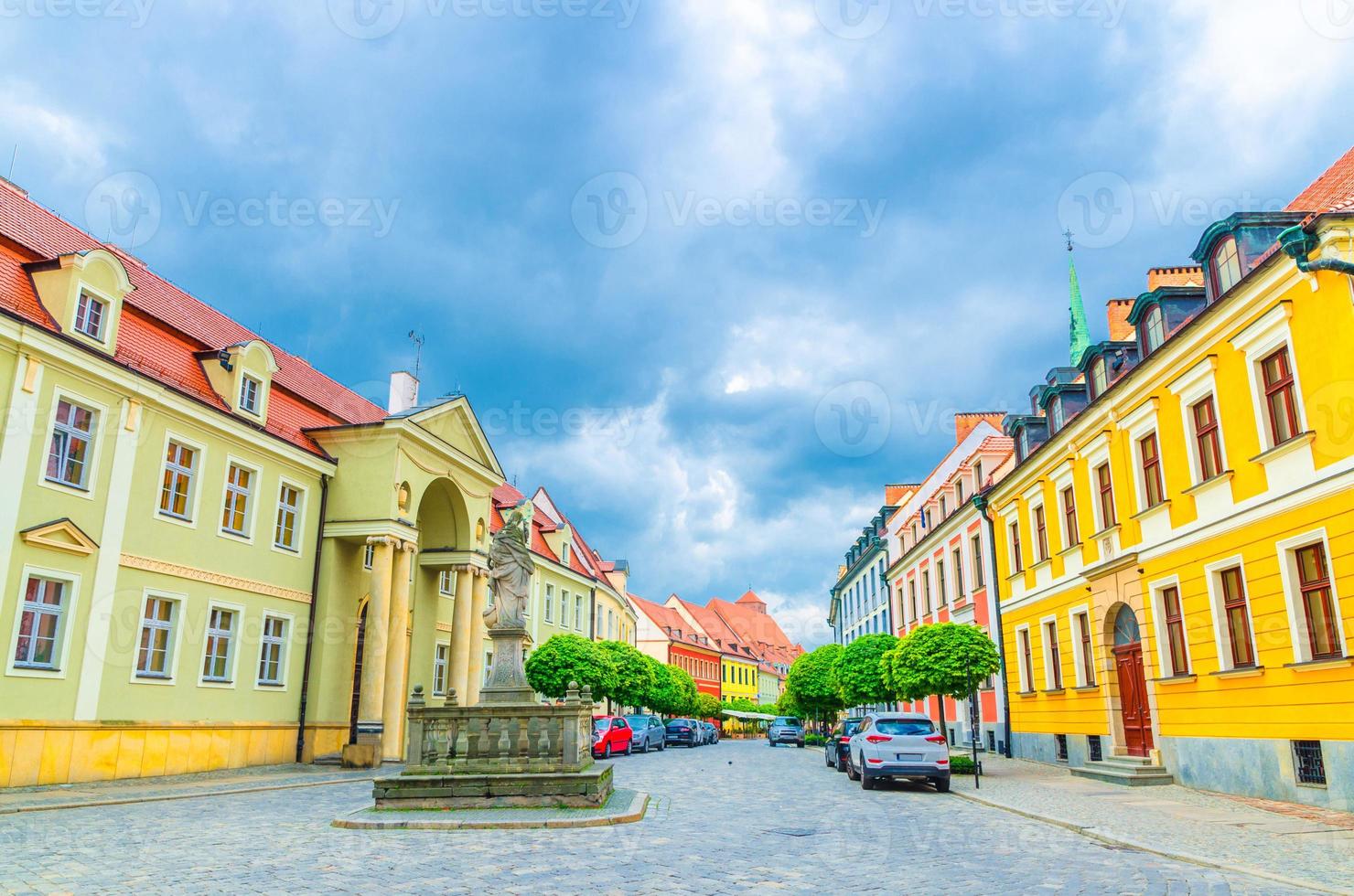 Cobblestone street with colorful buildings and Statue of Madonna and Child monument photo