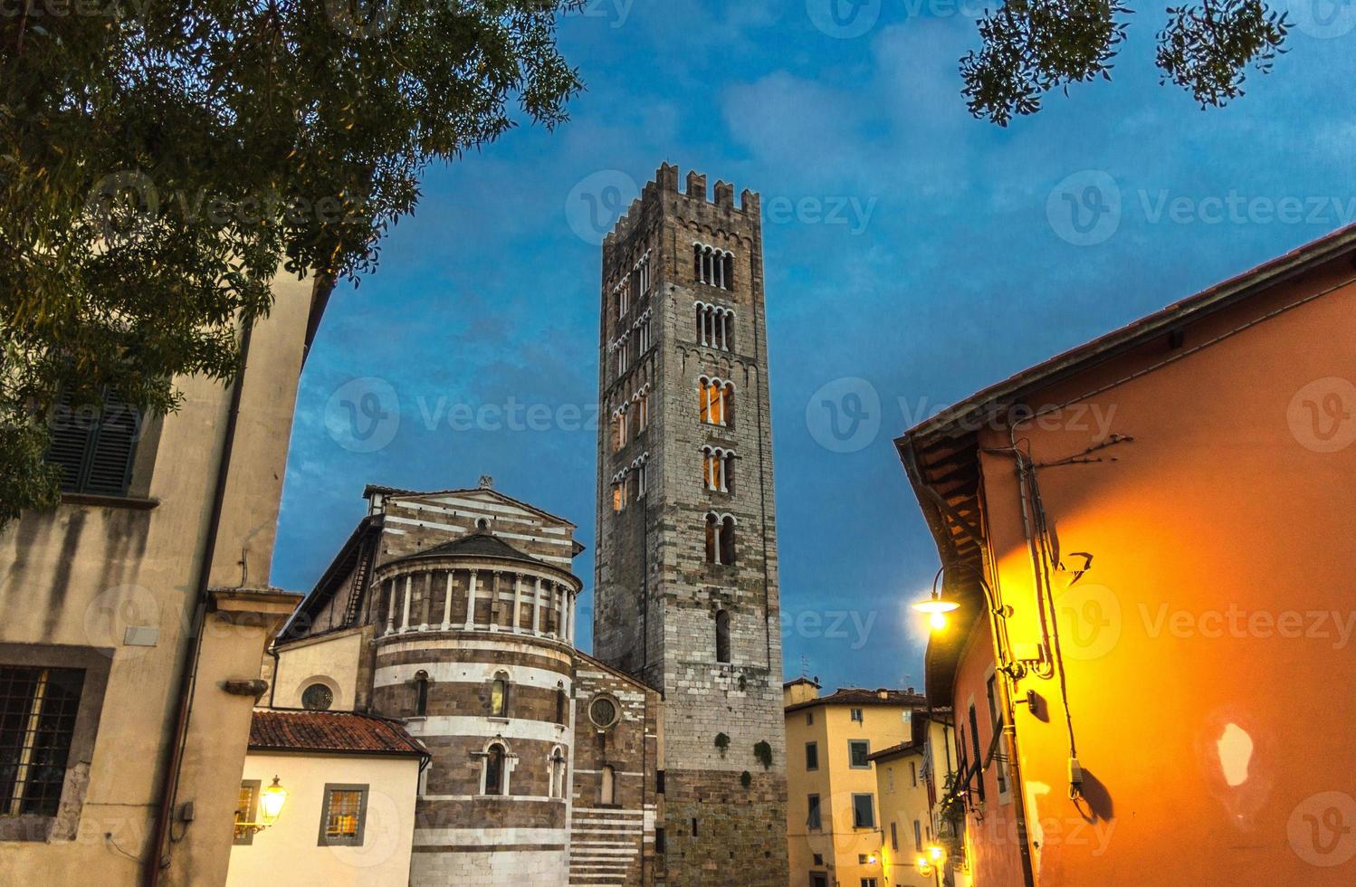 Bell tower of Chiesa di San Frediano catholic church and building with street lamp light on Piazza del Collegio square photo