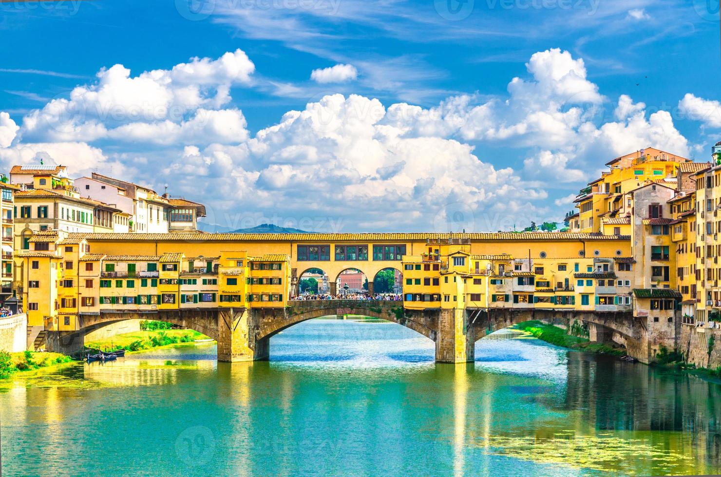 Ponte Vecchio stone bridge with colourful buildings houses over Arno River blue turquoise water photo