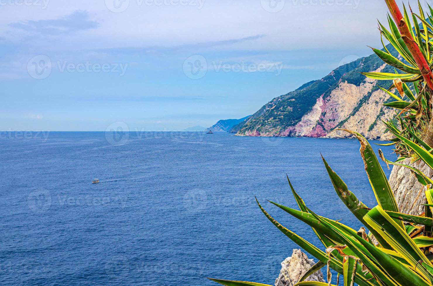 Grotta di Lord Byron with blue water, coast with rock cliff, yellow boat and blue sky near Portovenere town photo