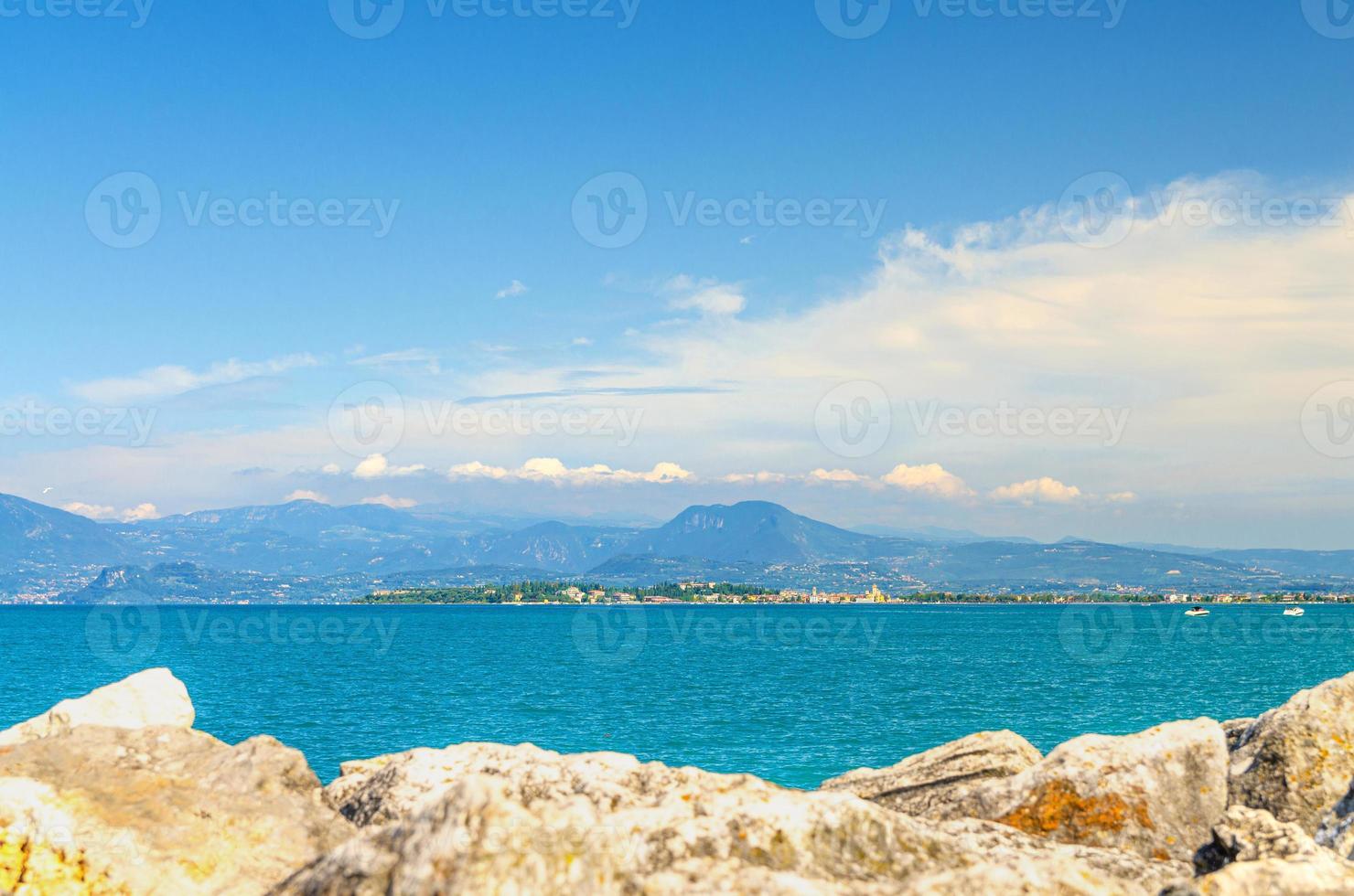 View from stone pier mole of Garda Lake azure water with Monte Baldo mountain range and Sirmione peninsula photo