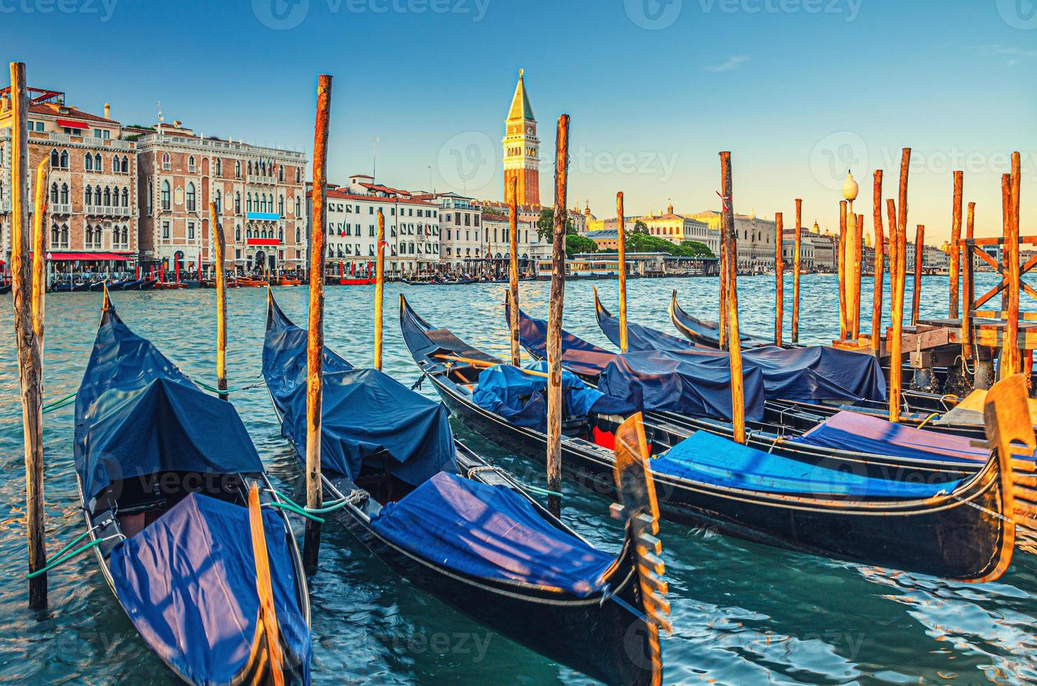 Gondolas moored docked on pier of Grand Canal waterway in Venice photo