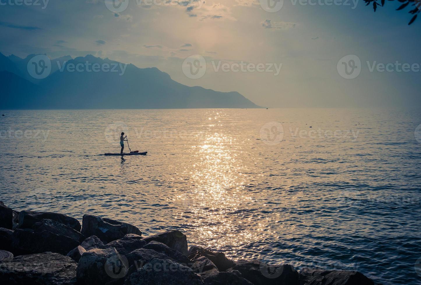 Man on a surfboard with paddle on Lake Leman, Switzerland photo