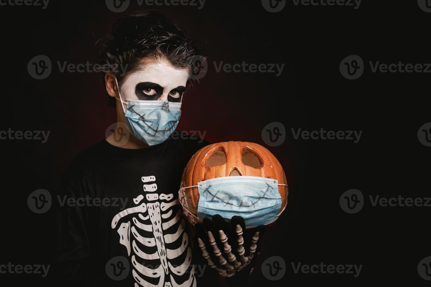 Happy Halloween.kid wearing medical mask in a skeleton costume with halloween pumpkin photo