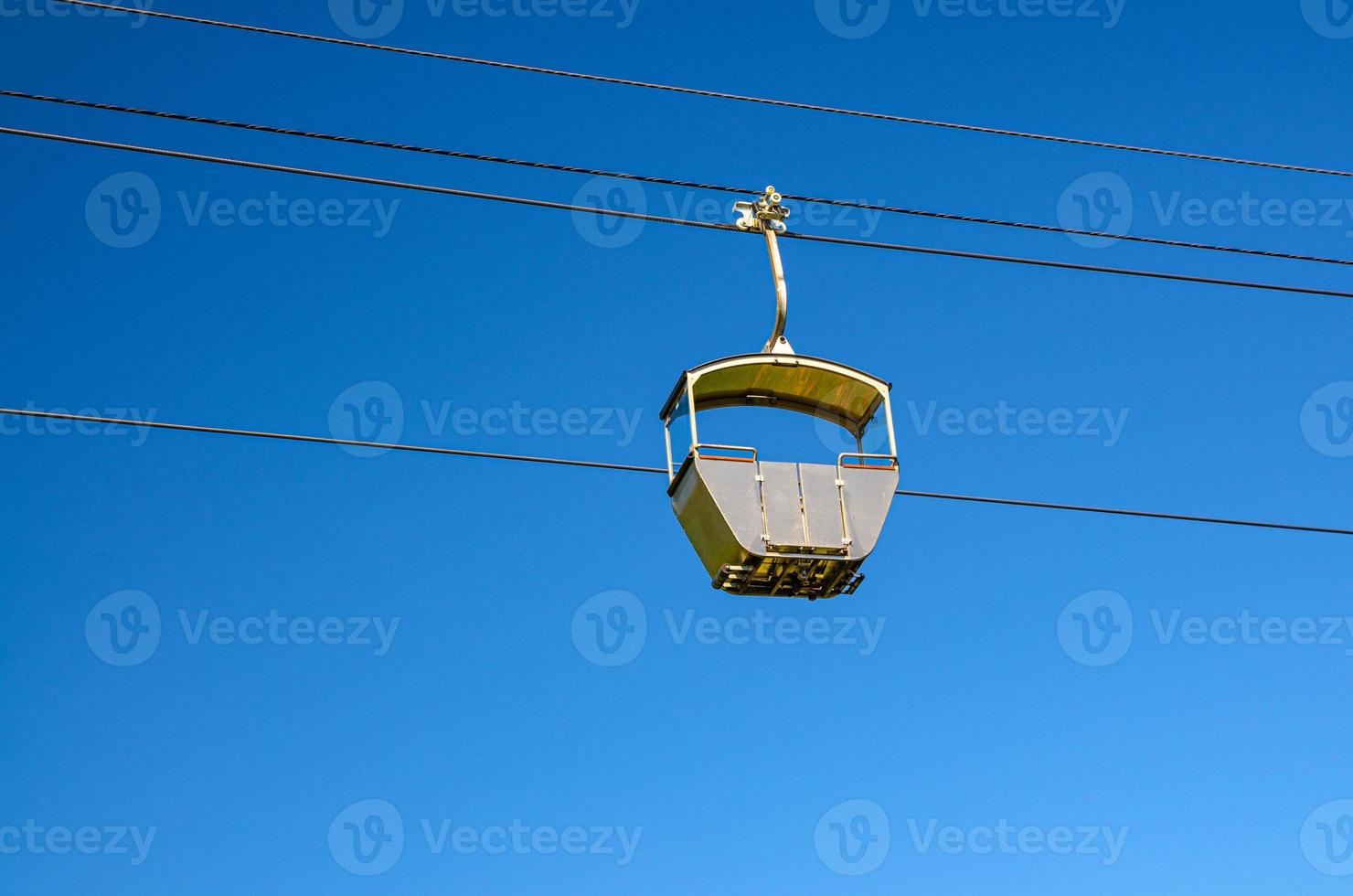 Cable car on rope of cableway, blue clear sky background in sunny summer day photo