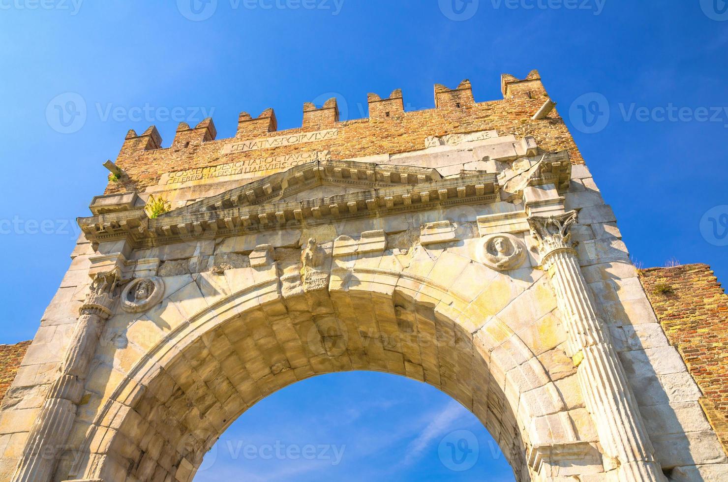 View from below of ancient brick wall and stone gate Arch of Augustus Arco di Augusto ruins photo