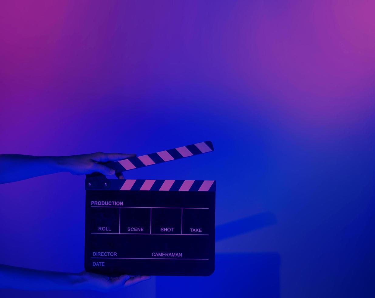 Hand holds empty film making clapperboard on color background in studio photo