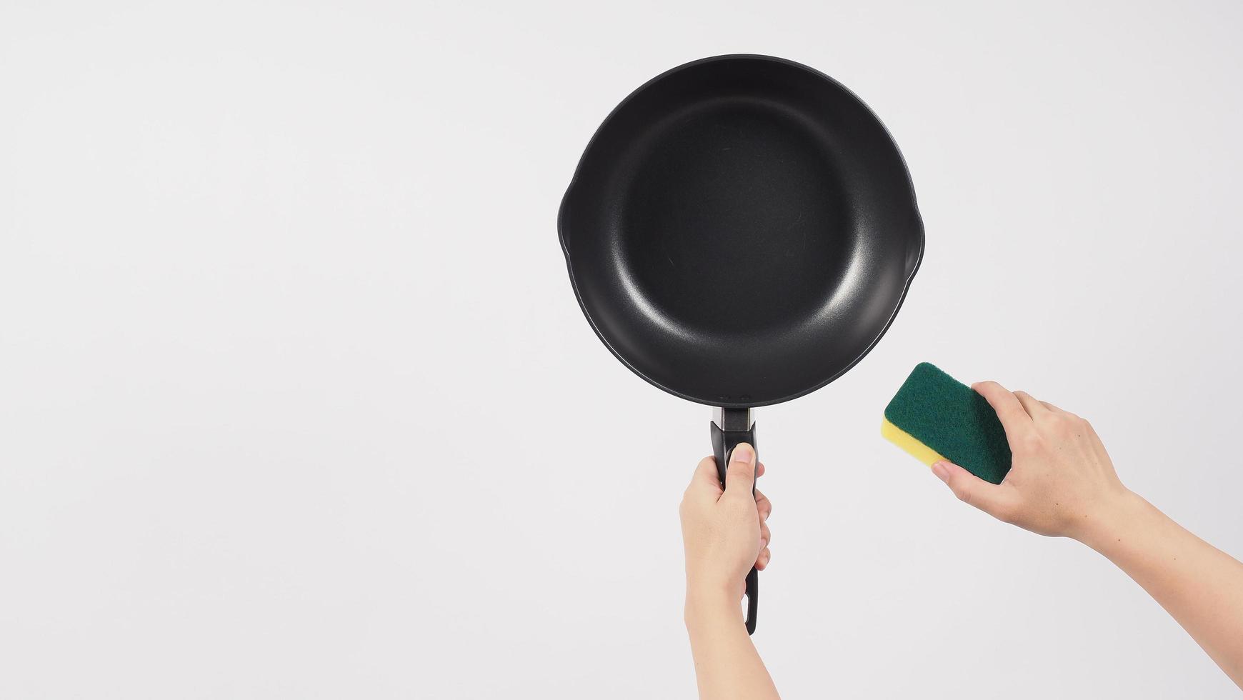 Hand cleaning the non stick pan with handy dish washing sponge photo