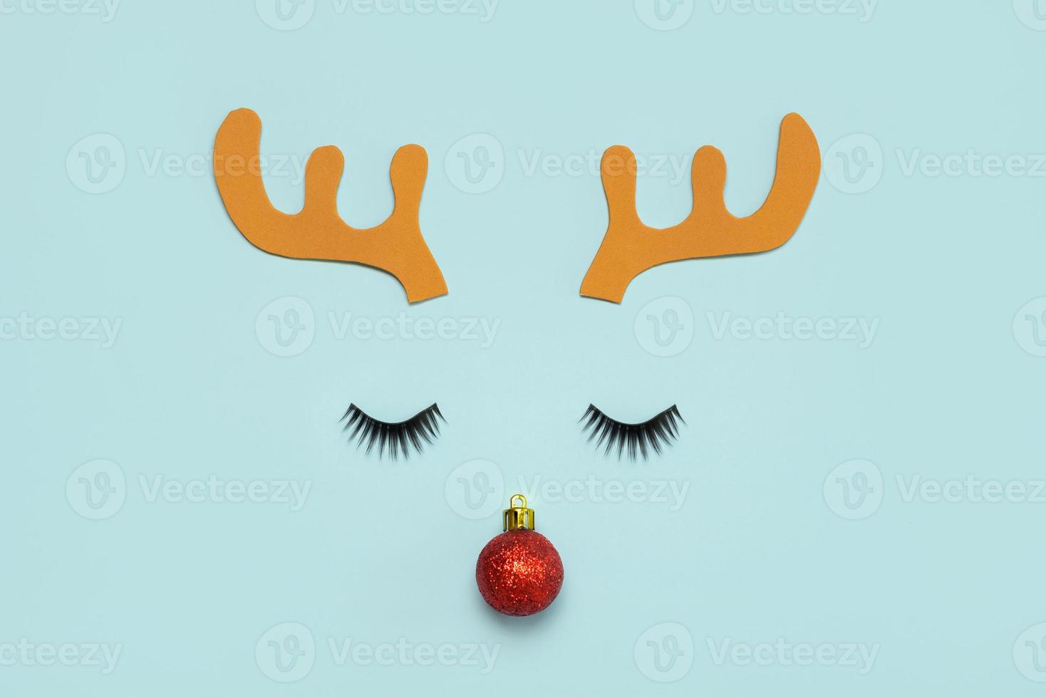 Merry Christmas.Christmas Rudolph reindeer horns with false eyelashes and red christmas ball.Christmas concept background photo