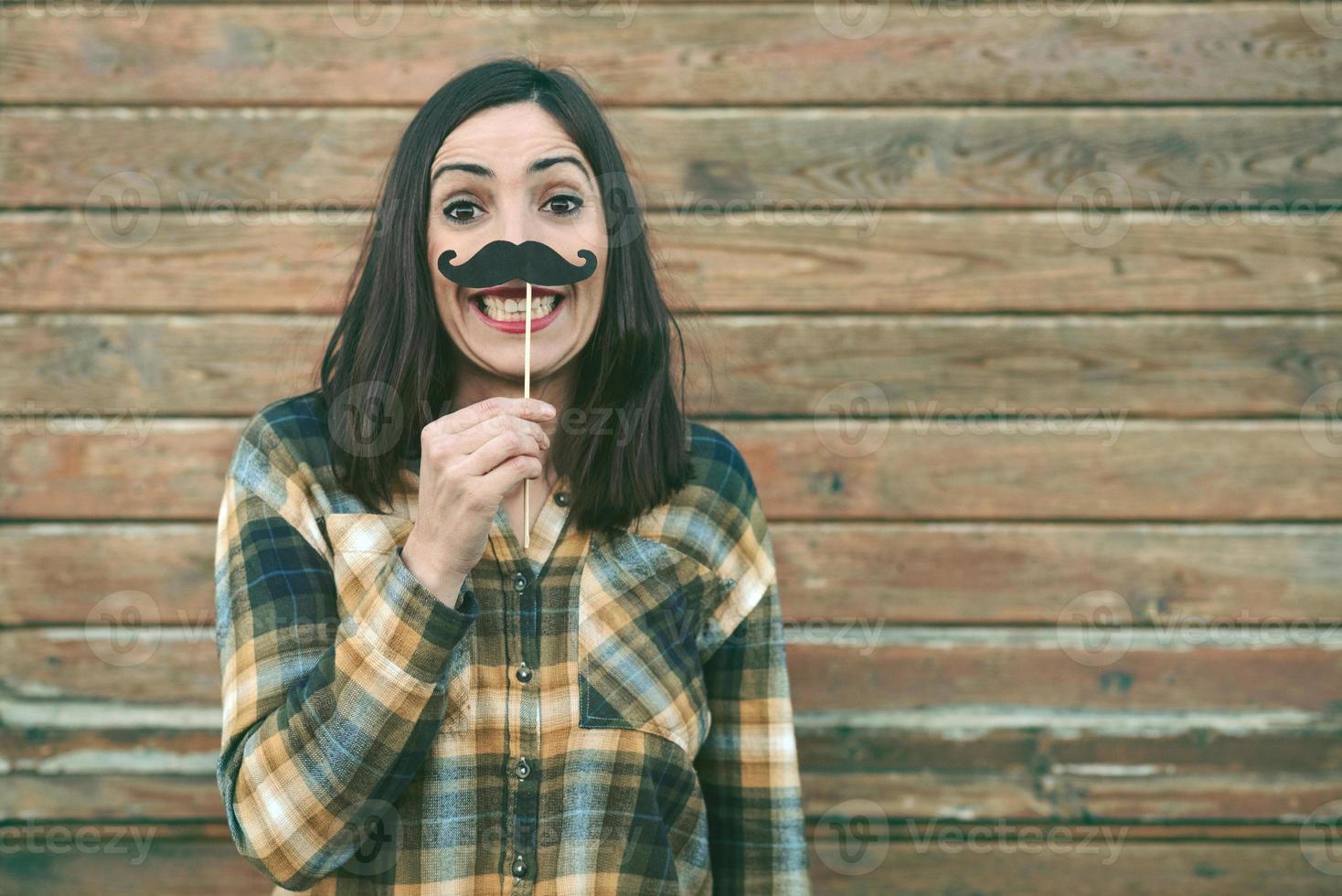 Funny young woman holding mustache on stick photo