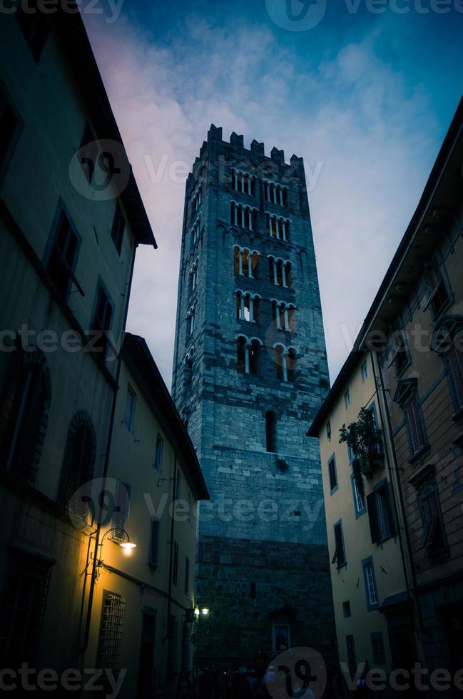 campanario de la iglesia católica chiesa di san frediano vista a través de la calle angosta con lámpara foto