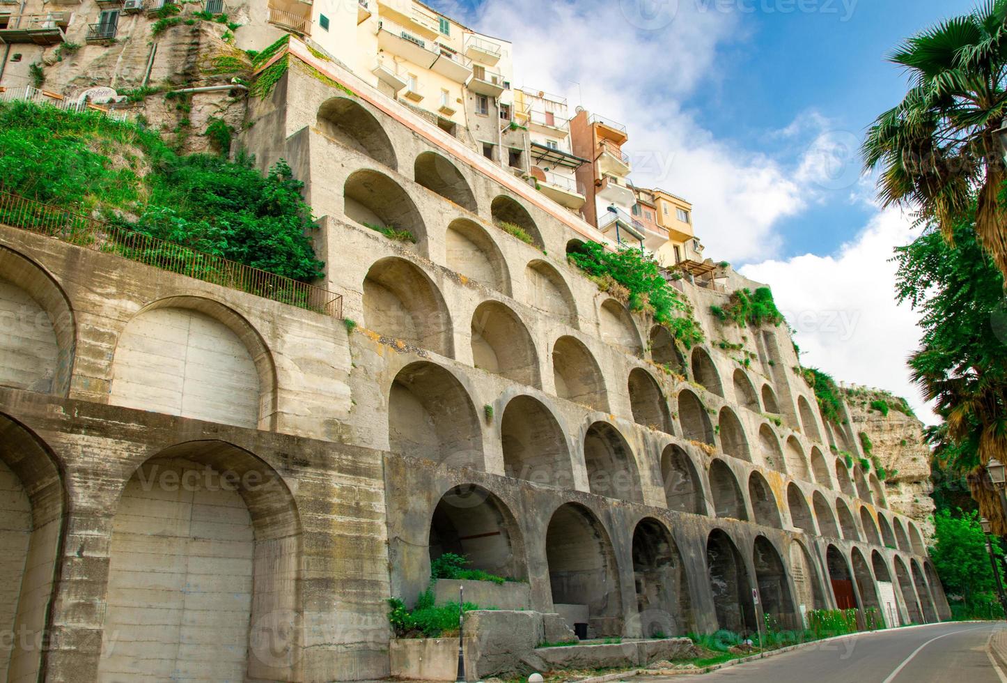 Wall with arches supportes buildings on rock in Tropea, Italy photo