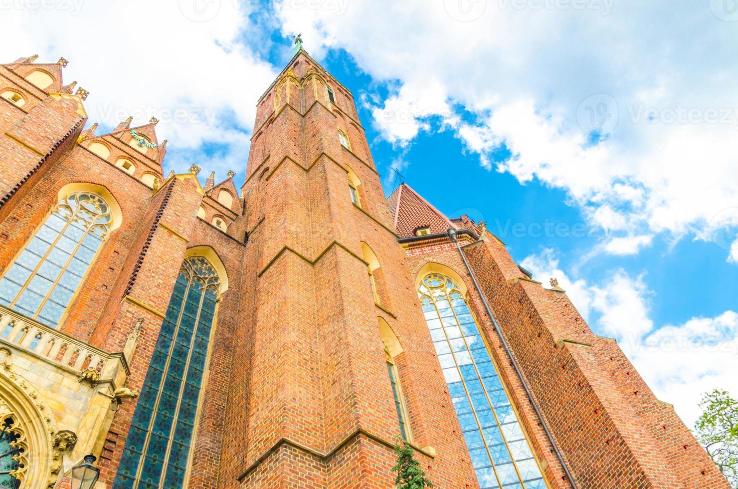 View from below of brick tower wall with spire of Collegiate Church of Holy Cross and St. Bartholomew catholic church photo