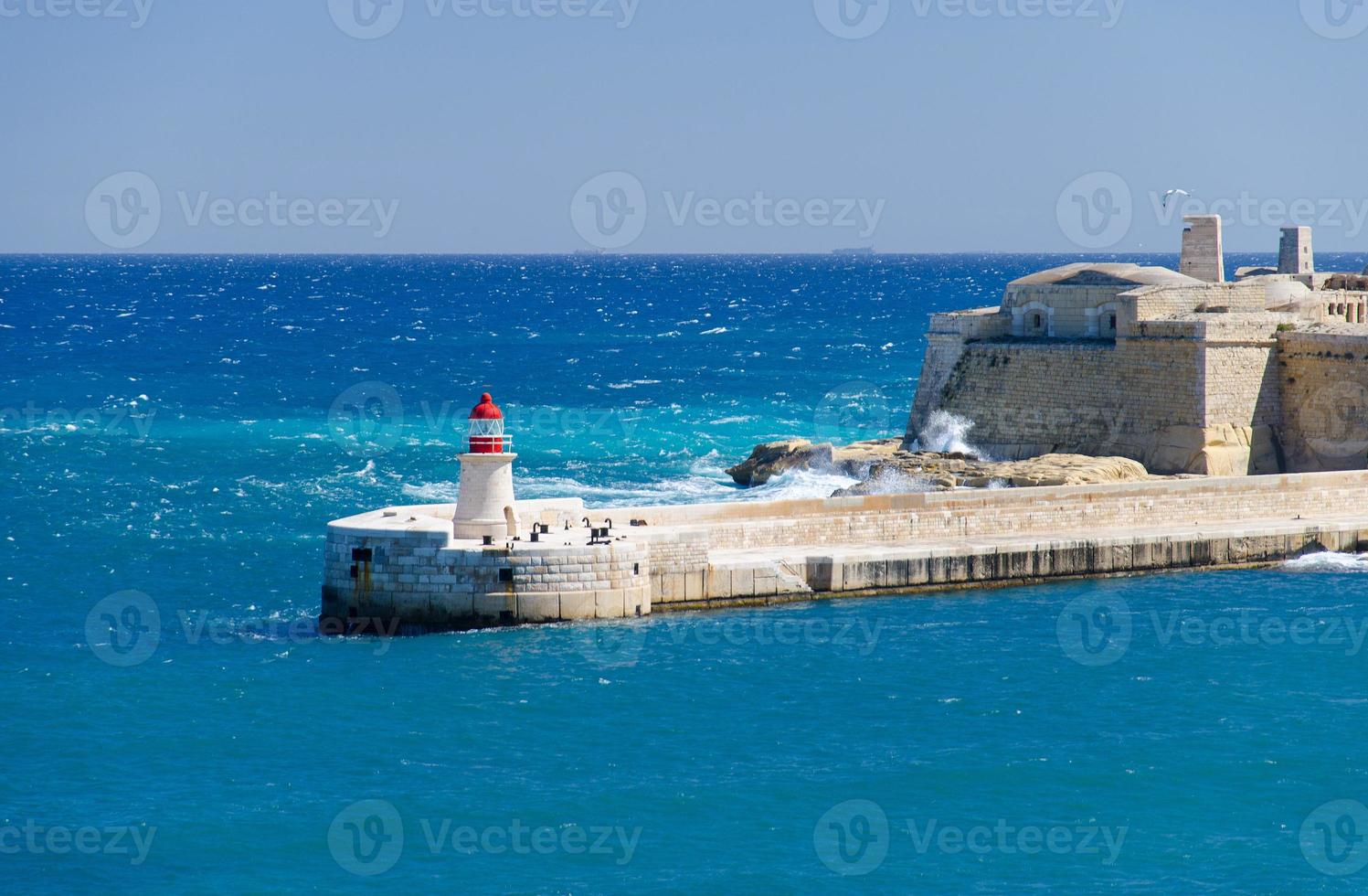 vista de la entrada del puerto con faro, valletta, malta foto