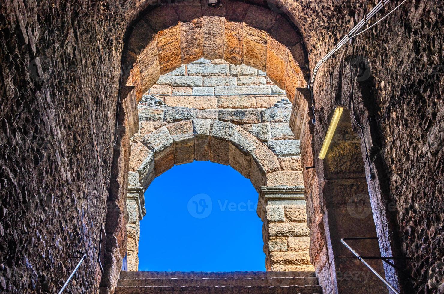 Blue clear sky through limestone brick arch window of The Verona Arena photo