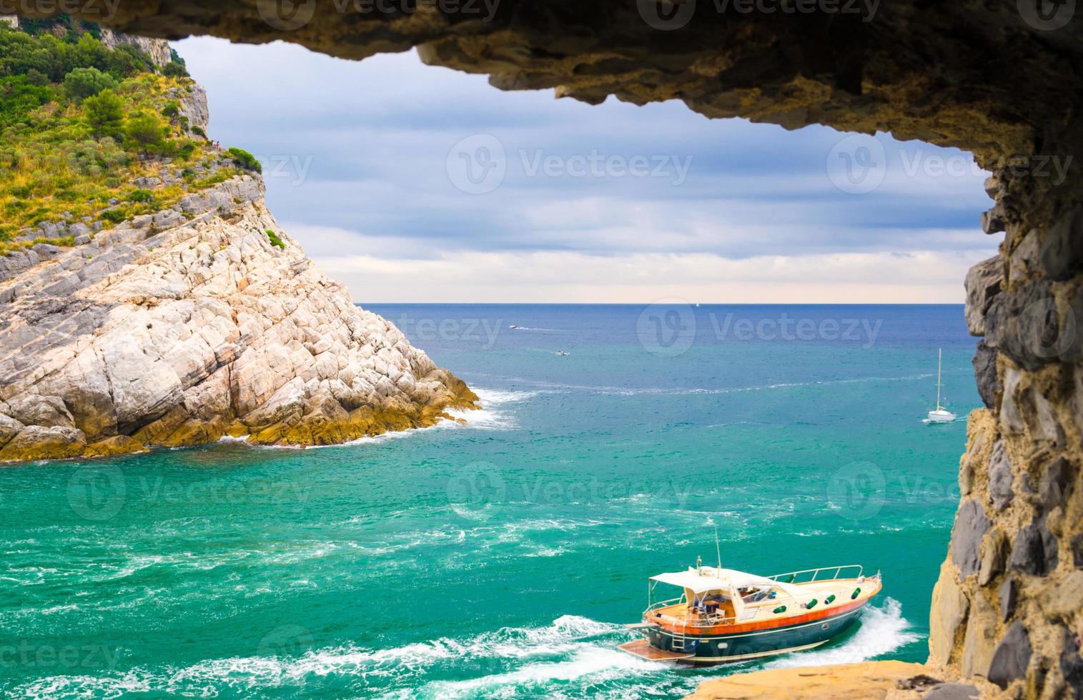 View of Ligurian sea water, rock cliff of Palmaria island and yacht through brick stone wall window photo