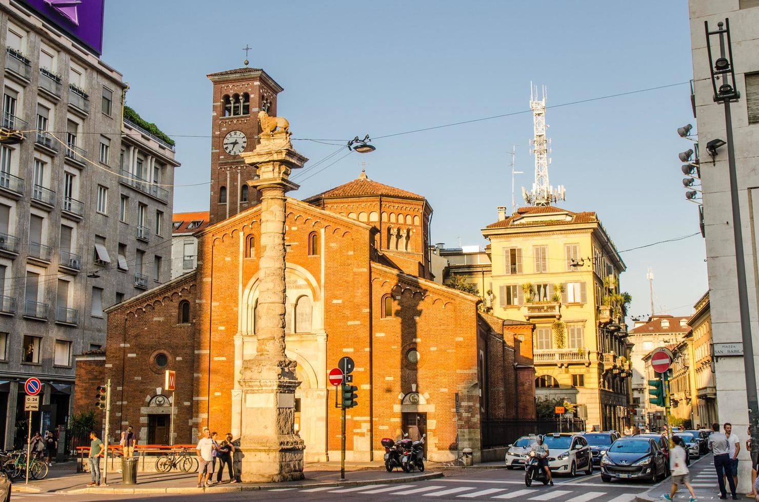 Basilica di San Babila church with clock tower and column with lion on top between modern buildings photo