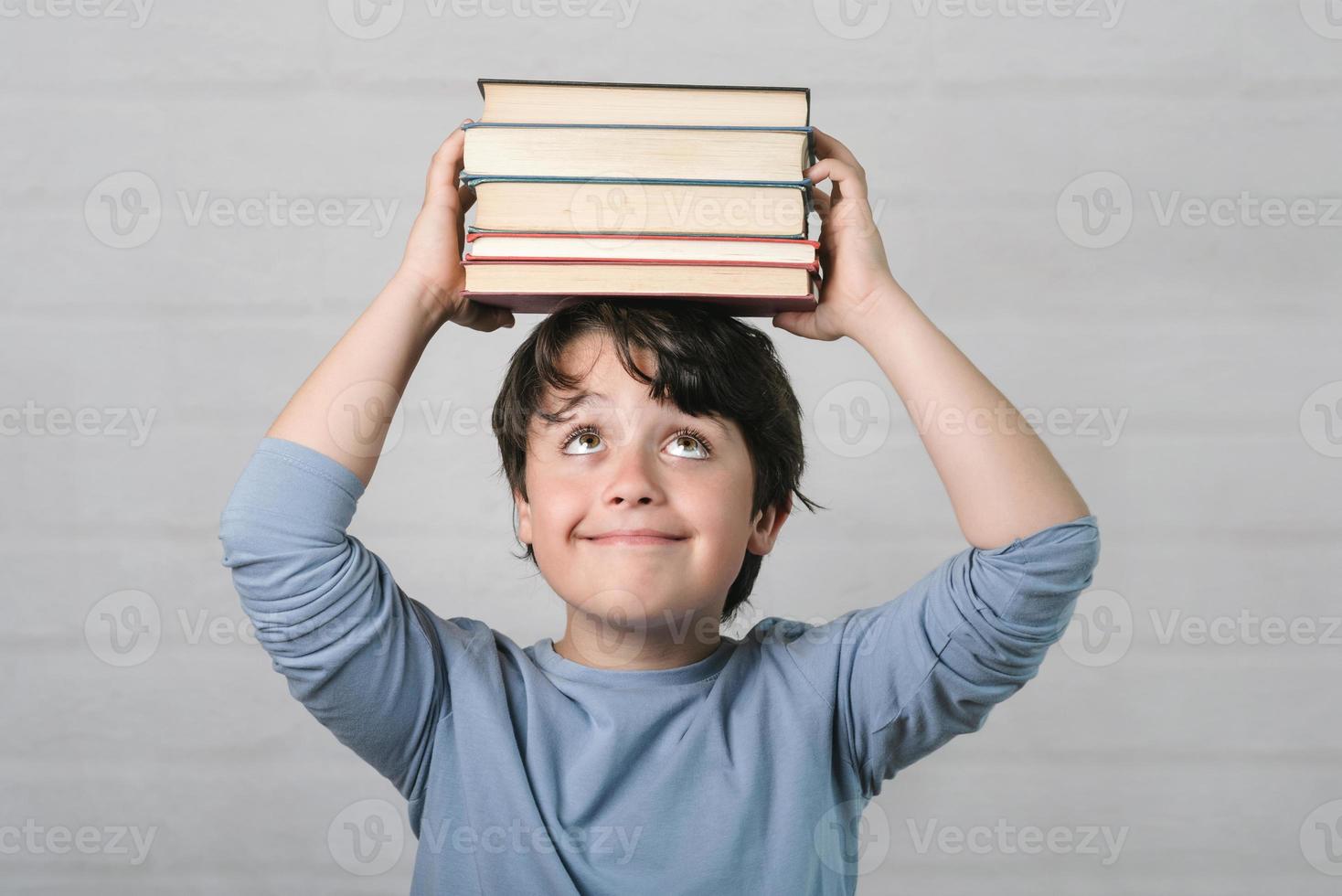 niño feliz con libros en la cabeza foto