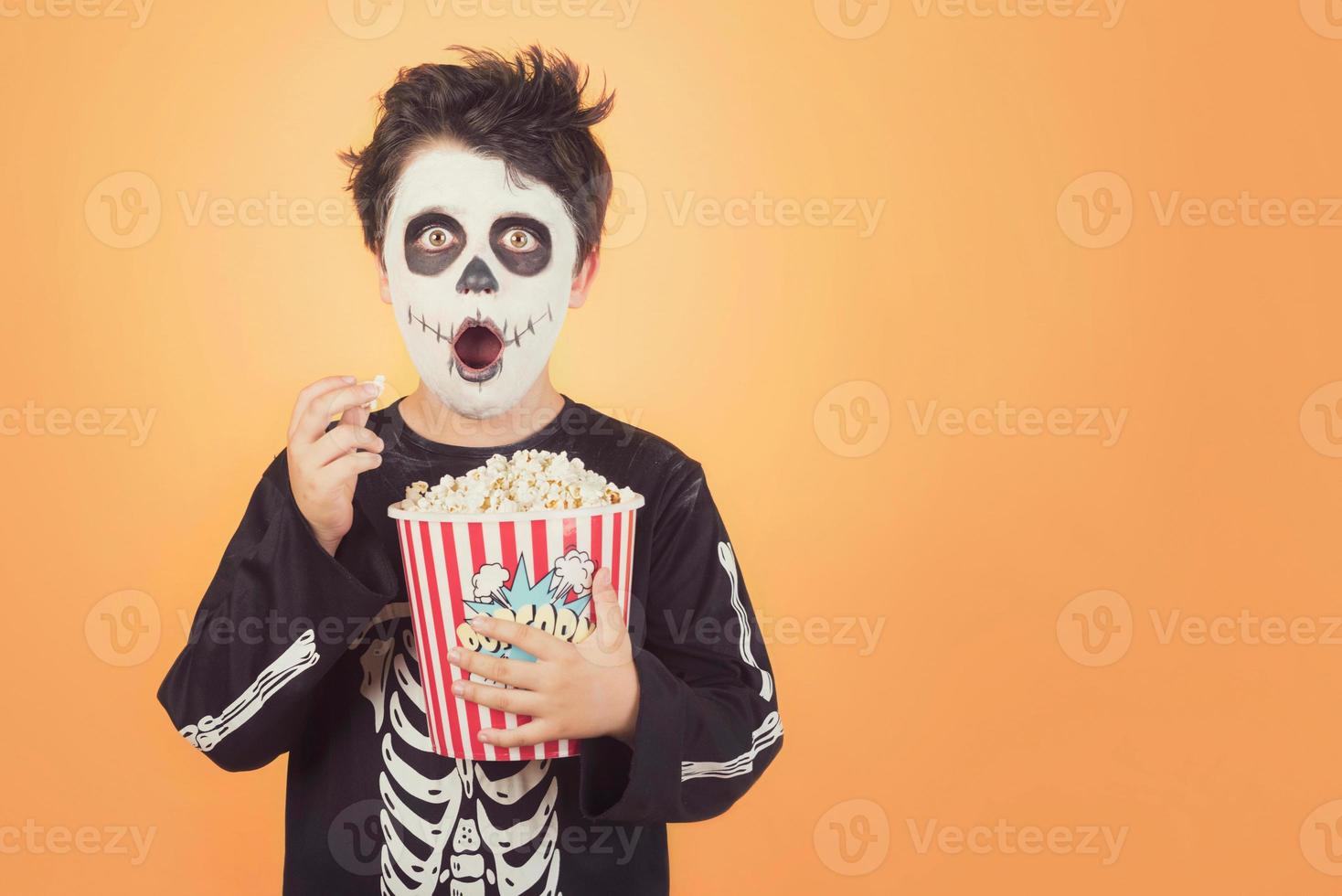 Happy Halloween.Surprised child in a skeleton costume with popcorn photo