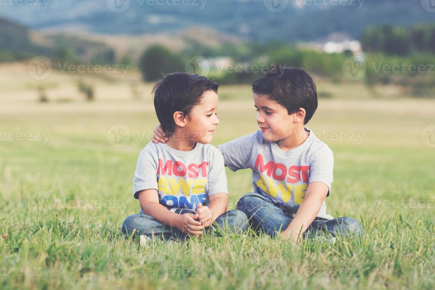 hermanos sonrientes sentados en el campo foto