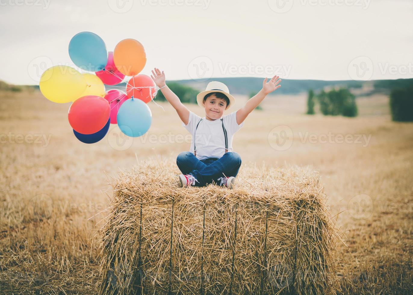 happy child with balloons in wheat field photo