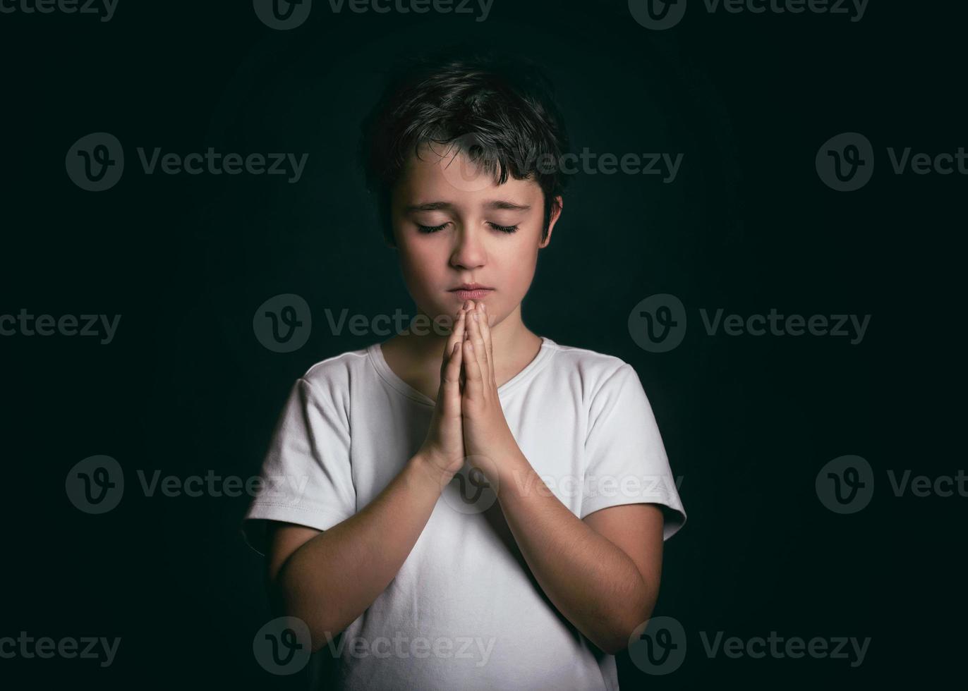child with hands clasped together praying photo