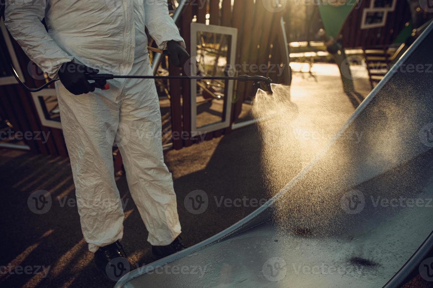 Cleaning and Disinfection on the playground in the sity complex amid the coronavirus epidemic Teams for disinfection efforts Infection prevention and control of epidemic Protective suit and mask photo